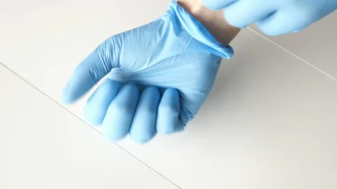 Showing how to put on putting on blue protective gloves on hands hand show Stock-Footage 129390418