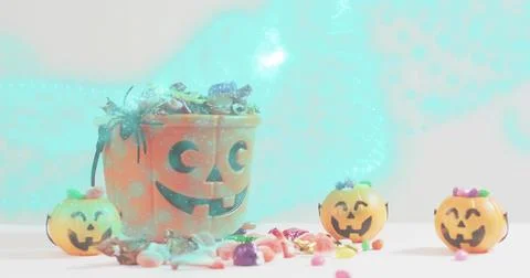 Showing large orange jack-o'-lantern bucket holding candy on white table with 3 Stock Photos