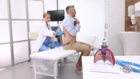 Showing lungs model while doctor pulmonologist auscultation a patient's back  Stock Footage 319929642
