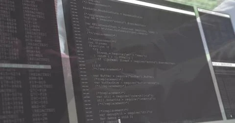 Showing multiple monitors displaying JS code and terminal logs at office desk, 库存照片