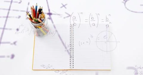 Showing open spiral notebook on white desk, with glass jar holding colored pe Stock-Fotos