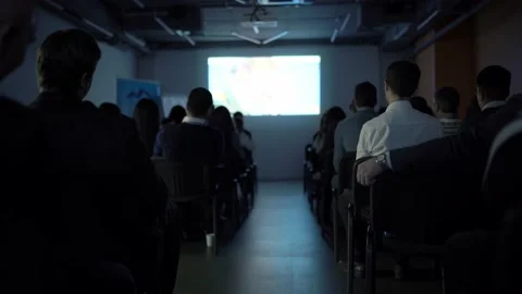 Showing a presentation on a screen in front of a large audience in the dark. Stock Footage 198518393