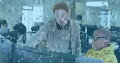 Showing redhead dev leaning over screen with headset pointing at code in office Stock Photos