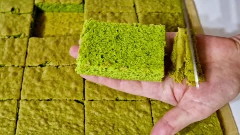 Showing soft texture of green matcha sponge cake by peeling top layer with knife Stock Footage 327258746