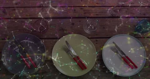 Showing three round plates with red-handled cutlery and glasses on wooden table, Stock Photos