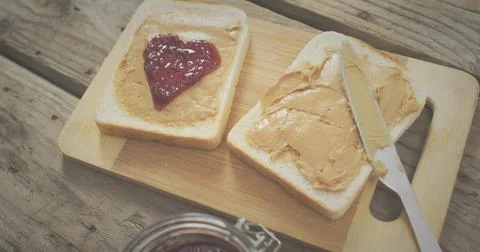 Showing two bread slices with peanut butter on bamboo board at kitchen table, Stock Photos