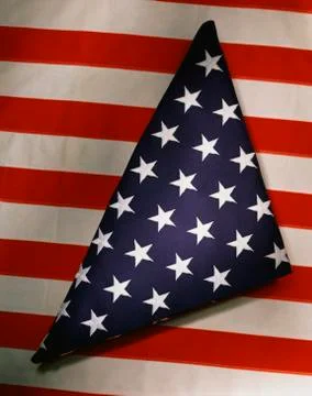 This shows a triangularly folded American flag sitting on top of another Stock Photos