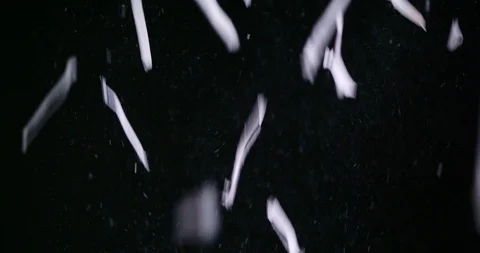 Shredded bits of paper filling screen as they fall against black background Stock Footage 123734170