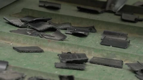 Shredded black plastic chunks scattered on conveyor belt in recycling factory Stock Footage 334167471