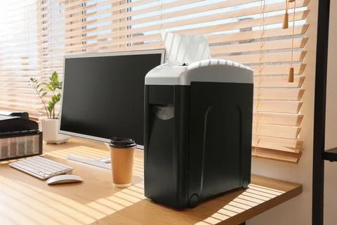 Shredder with coffee cup and computer on desk in modern office Stock Photos
