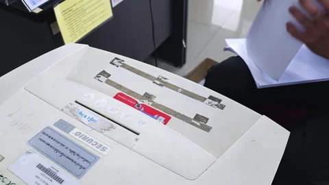 Shredding a stack of printed documents using an electric shredder to Stock Footage 257534342