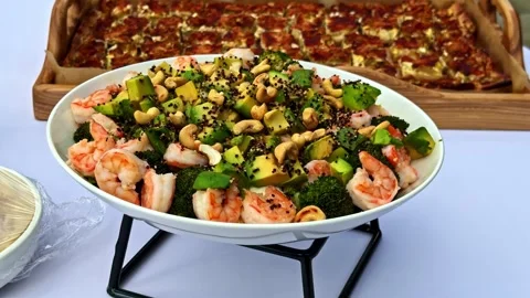 Shrimp and Vegetable Salad with Nuts Served Outdoors Beside Baked Dish on Table Stock Footage 337386406