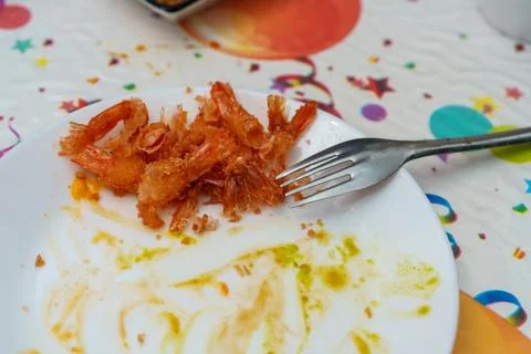 Shrimp plate with fork left at a table after a meal during a gathering or par Stock-Fotos