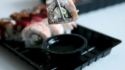 Shrimp sushi roll dipped in soy sauce with dripping sauce and metal chopsticks Stock Footage 346175795