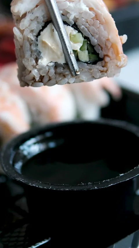 Shrimp sushi roll dipped in soy sauce with dripping sauce and metal chopsticks Stock Footage 346187583