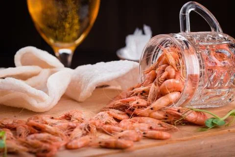 Shrimps on a wooden board against the background of a glass of beer Stock Photos