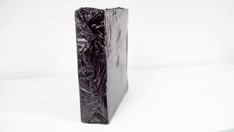 Shrink wrapping a box  with black shrink wrap with a heat gun Stock Footage 98618903