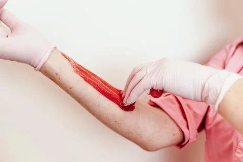 Shugaring master applying thick sugar paste on lady's hand, removing unwanted Stock Photos