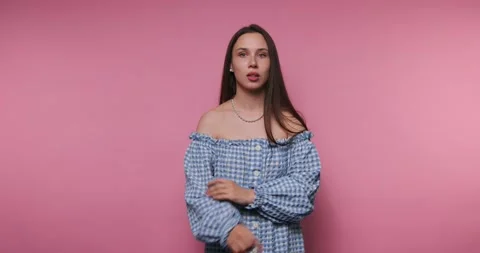 Shushing gesture with playful expression in front of a pink background Stock Footage 316182834