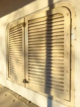 Shutter on a wall under sunset light in a quiet setting near an old building Stock Photos