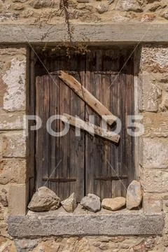 Shuttered and barred old window in a stone wall Stock Photos