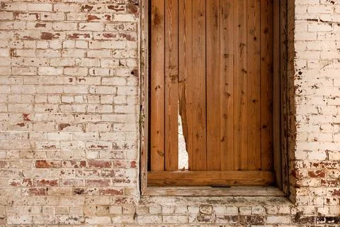 Shuttered window with break in shutter and old white washed brick wall. Stock Photos