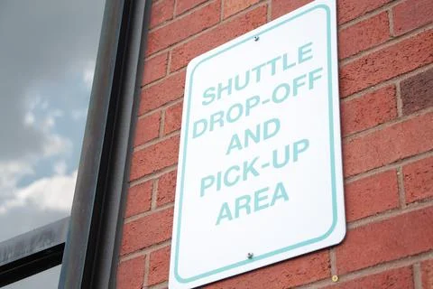 Shuttle drop off and pick up area rectangle vertical sign on red brick wall Stock Photos