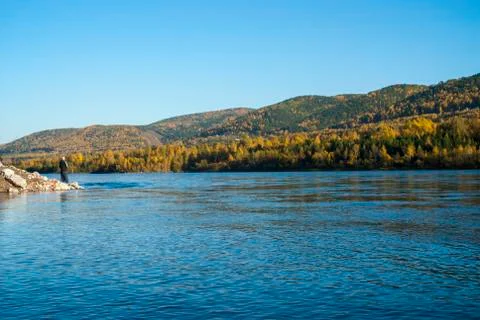 Siberian river and mountains covered by forest with a fisherman in the backgr Stock Photos