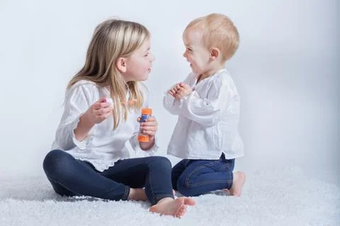 Siblings (2-3, 6-7) playing with bubble wand Stock Photos