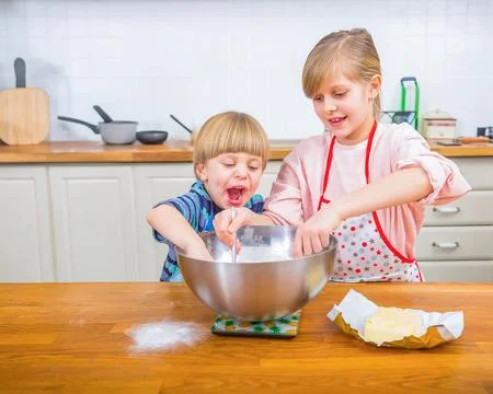 Siblings Baking Together in a Bright Kitchen Showcasing Fun and Family Bondin Stock Photos
