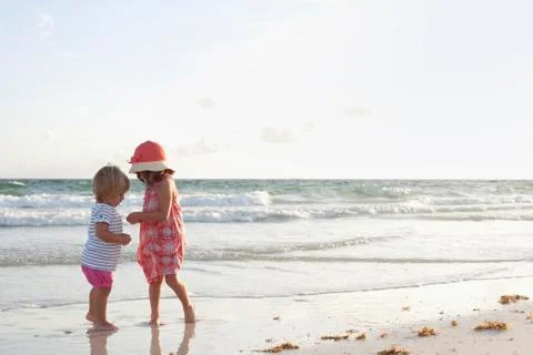Siblings exploring on the beach at sunset Stock Photos