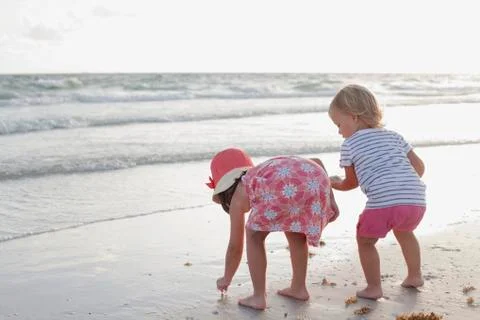 Siblings exploring on the beach at sunset Stock Photos