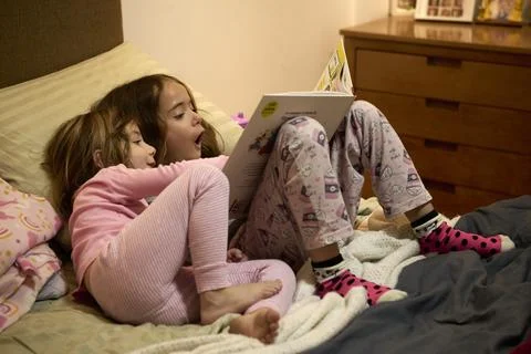 Siblings having fun while reading a great book together Stock Photos