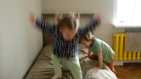 Siblings jumping on bed at home Video stock 129308431