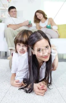 Siblings looking at camera with their parents sitting on sofa at background Stock Photos
