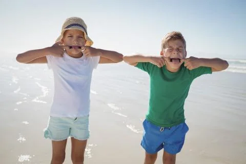 Siblings making teasing faces at beach Stock Photos