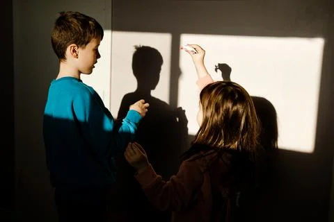 Siblings Playing with Light and Shadow Indoors Stock Photos