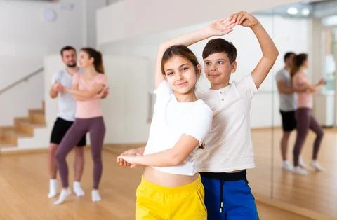 Siblings practicing active dance in pairs Stock Photos