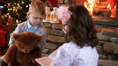 Siblings reading a book at fireplace Stock-Footage 94207407