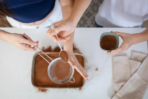 Siblings sifting cocoa powder while baking cake Fotos Stock