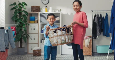 Siblings stand in the middle of the laundry room holding a bowl of clothes near 库存影片 199976963