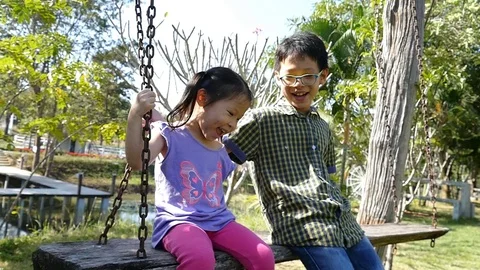 Siblings swinging in time together Stock Footage 72978736