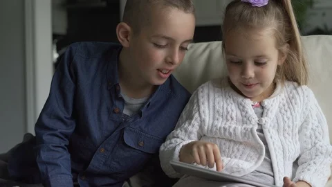 Siblings using the tablet together in living room Stock Footage 100174397