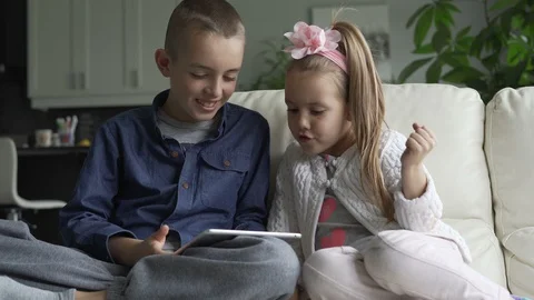 Siblings using the tablet together in living room Stock Footage 100174857