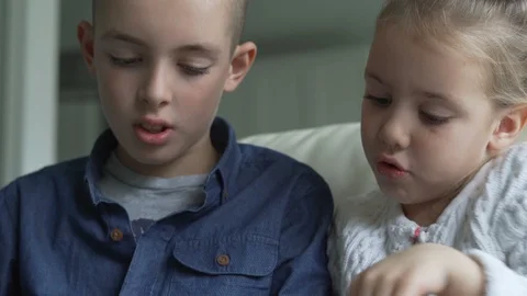 Siblings using the tablet together in living room 스톡 동영상 100174910