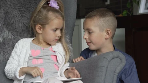 Siblings using the tablet together in living room Stock Footage 100175072