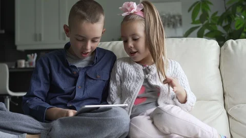 Siblings using the tablet together in living room Stock Footage 100175100