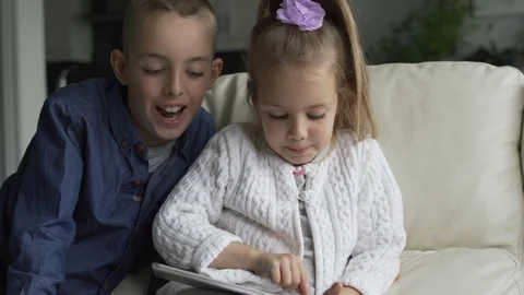 Siblings using the tablet together in living room Stock Footage 100175141