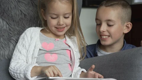 Siblings using the tablet together in living room Stock Footage 100175160