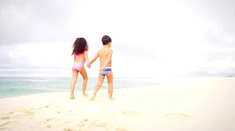 Siblings walk down a beach in Brazil Stock Footage 49476530
